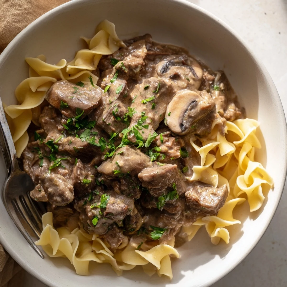 Creamy Slow Cooker Beef Stroganoff served over tender egg noodles and garnished.  