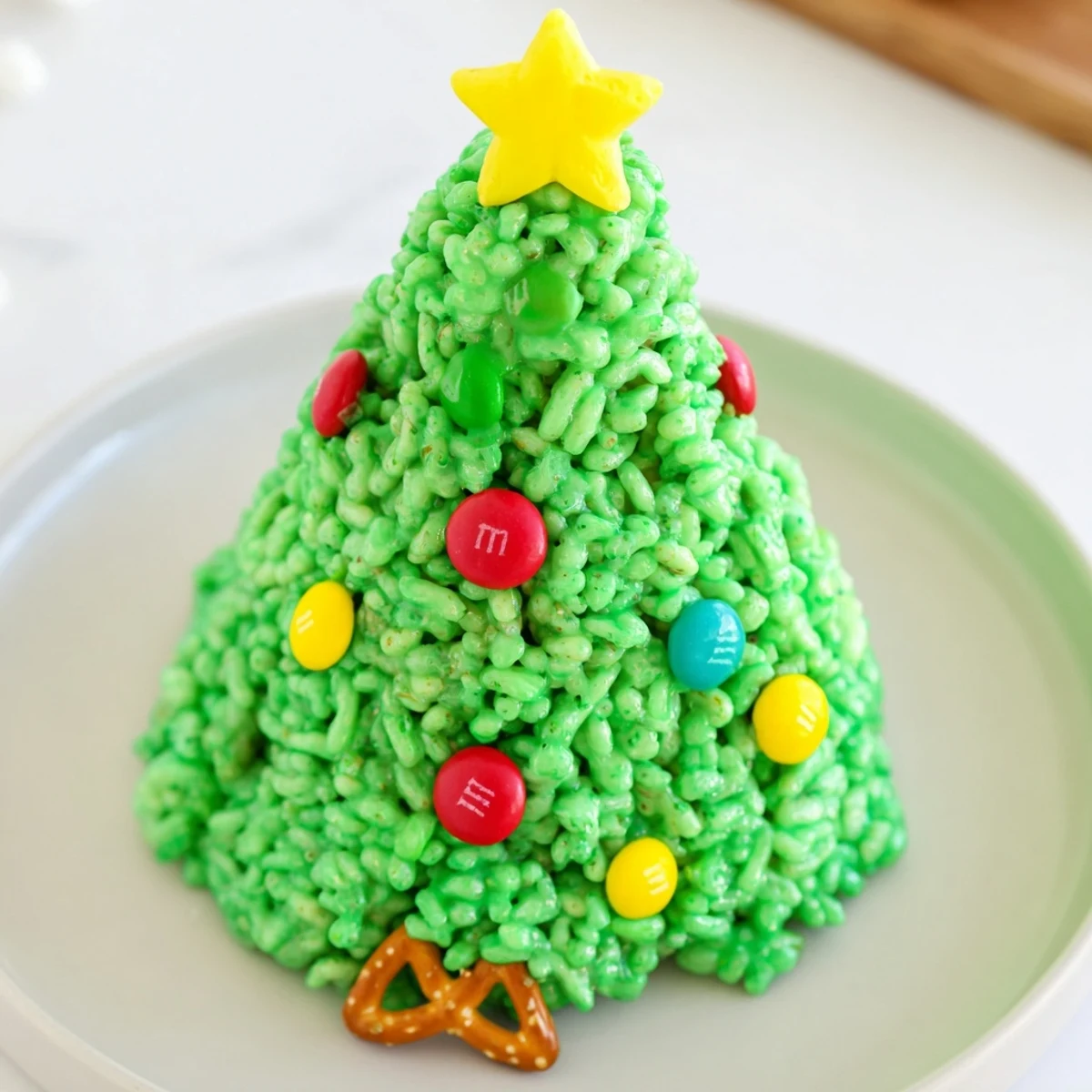 A close-up of vibrant green Christmas Tree Rice Crispy Treats, decorated with colorful candies and stars.