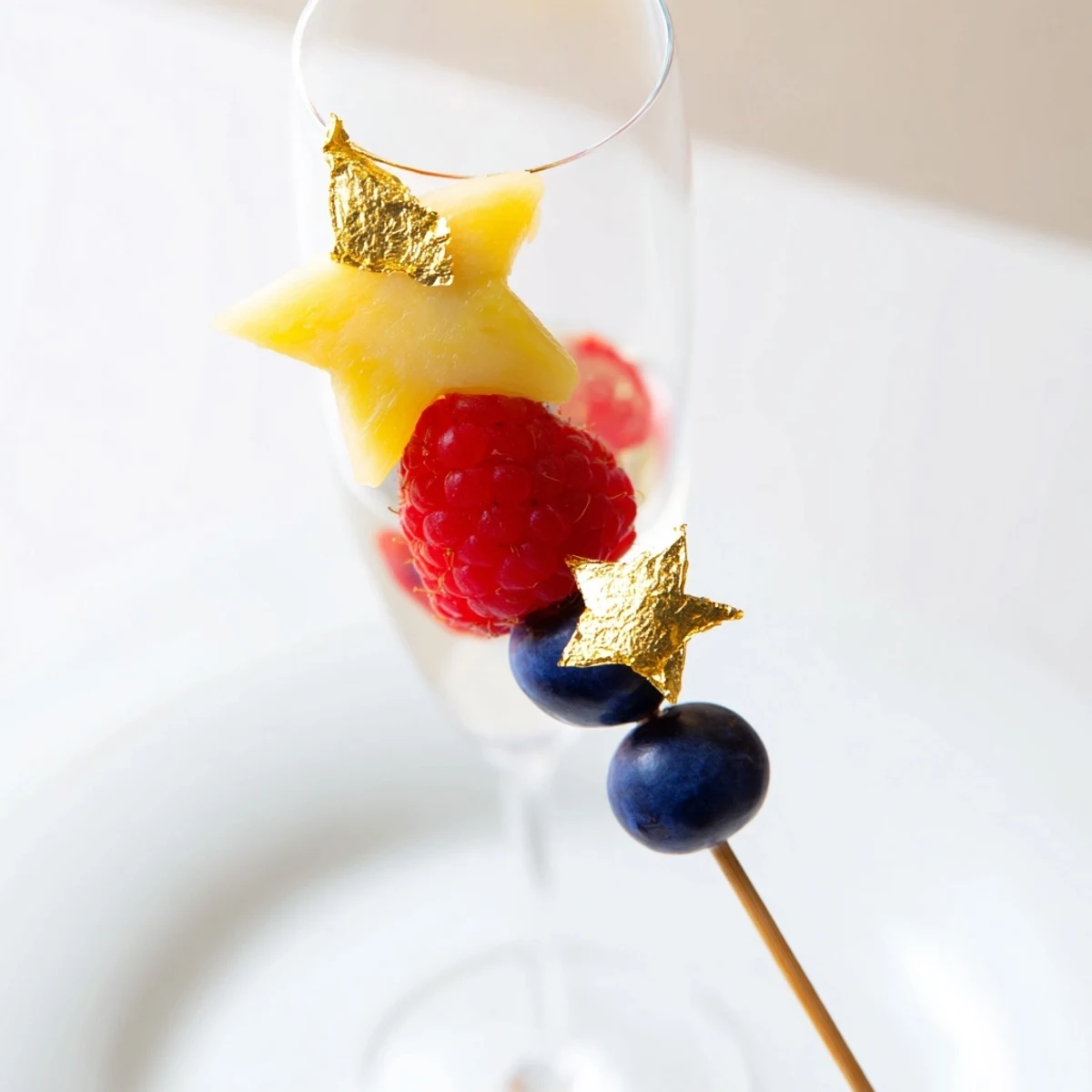 These elegant fruit garnishes for champagne flutes showcase beautifully arranged slices and fresh raspberries ready to be enjoyed.