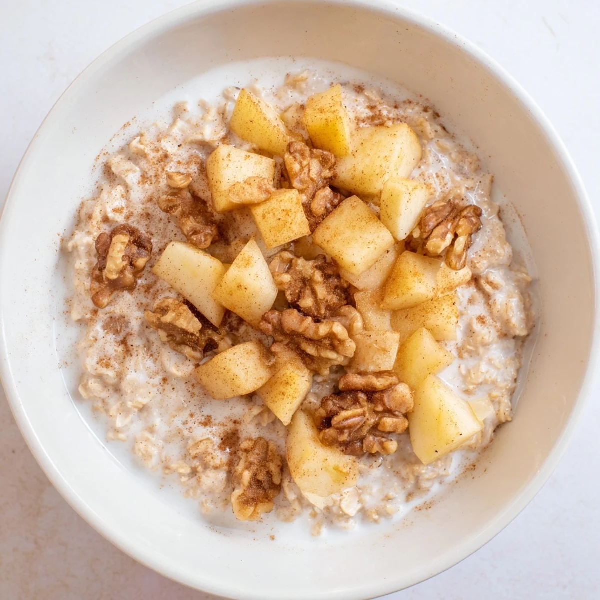 Warm apple slices topping a comforting bowl of Apple Pie Oatmeal, perfect for a cozy morning.