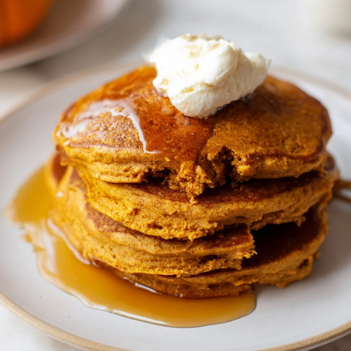 Golden brown Fluffy Pumpkin Spice Pancakes stacked high, drizzled with maple syrup; a breakfast dream.