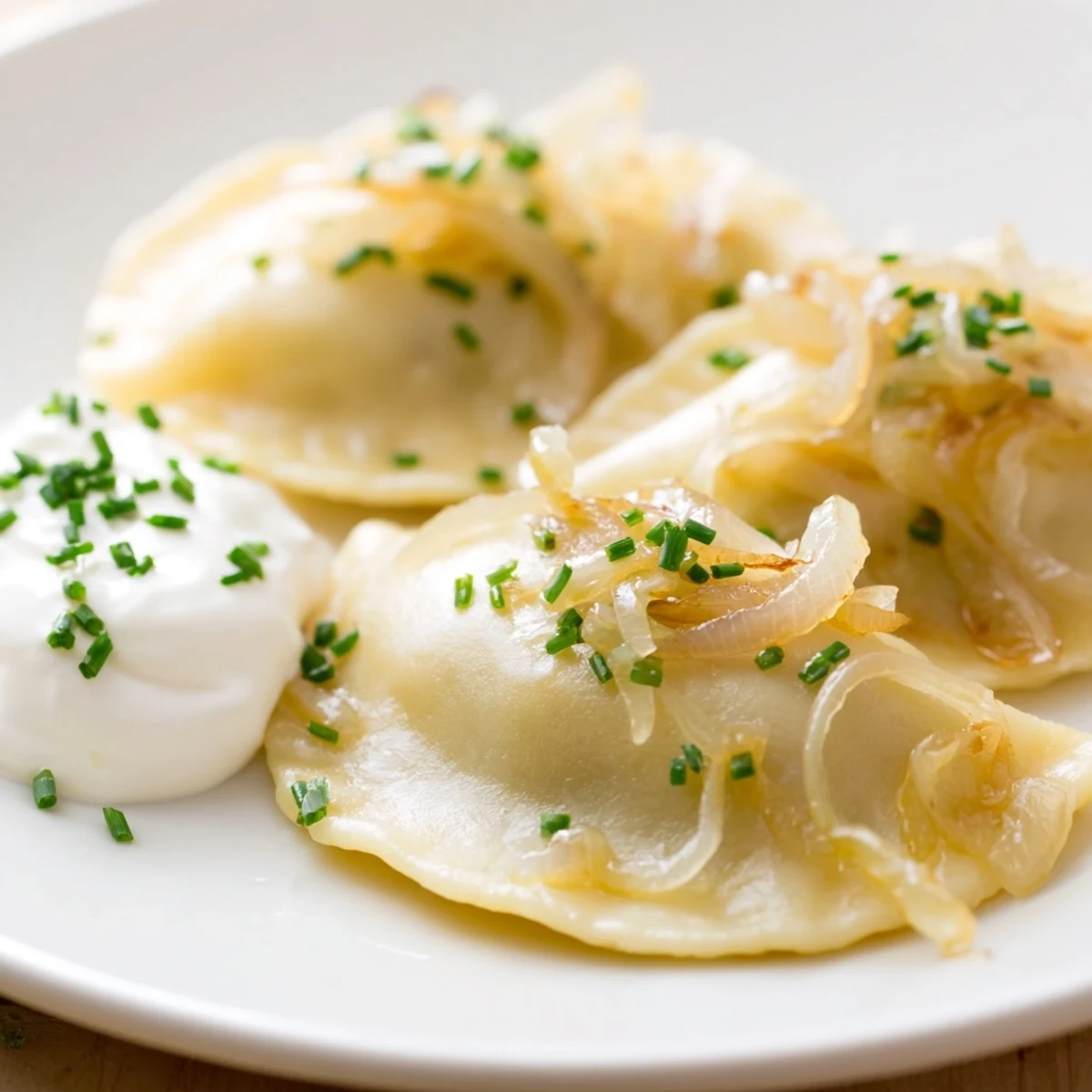 Warm, comforting plate of Polish pierogi, a vegetarian delight, topped with sour cream.