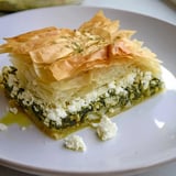 A close-up of a bubbling, savory Greek spanakopita, showing the delicious spinach and feta filling.