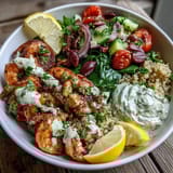 In this healthy Mediterranean Shrimp Bowl, succulent shrimp sit atop a bed of spinach, olives, and red onion, ready for a squeeze of lemon.