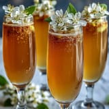 Elegant Elderflower Guava Mimosa in a champagne flute with edible flowers and fresh guava slice, perfect for brunch celebrations.  