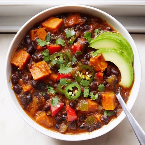A steaming bowl of Spicy Black Bean and Sweet Potato Chili topped with fresh avocado.  