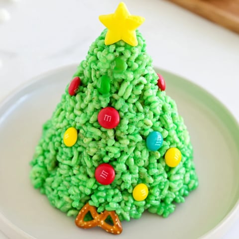 A close-up of vibrant green Christmas Tree Rice Crispy Treats, decorated with colorful candies and stars.