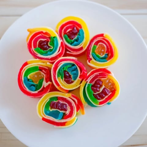 Vibrant Rainbow Candy Roll Ups, layered with colorful gummies, ready for a sweet party snack.