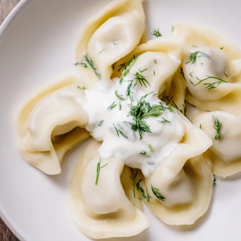Steaming Russian pelmeni, perfectly formed, served with creamy sour cream, ready to enjoy this hearty meal.
