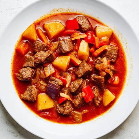 A steaming bowl of Hungarian Goulash Stew with tender beef and vibrant red peppers.