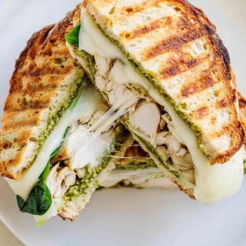 Golden-brown grilled Chicken Pesto Panini on ciabatta, oozing melted mozzarella with fresh basil pesto.  