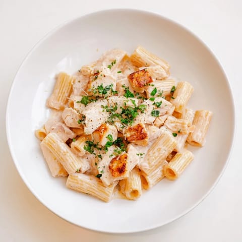 A close-up of creamy, flavorful Creamy Garlic Parmesan Chicken Rigatoni, garnished with parsley and cheese.