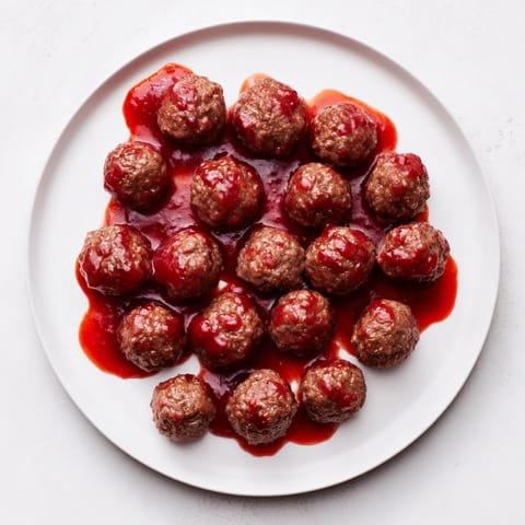 Savory ground beef meatballs swimming in a rich, shiny cherry glaze, perfect for a party.