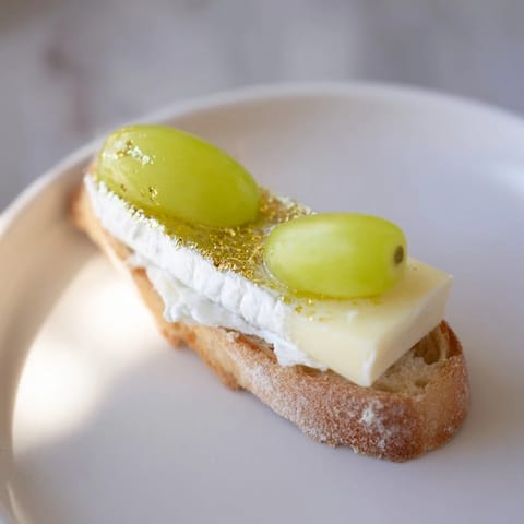 Tiny Sparkling Champagne Toast appetizers topped with cheese and prosecco-soaked grapes, beautiful for entertaining.