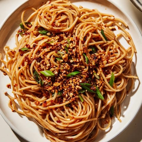 Tempting view: Spicy Garlic Chili Oil Noodles coated in flavorful sauce, garnished with fresh scallions.