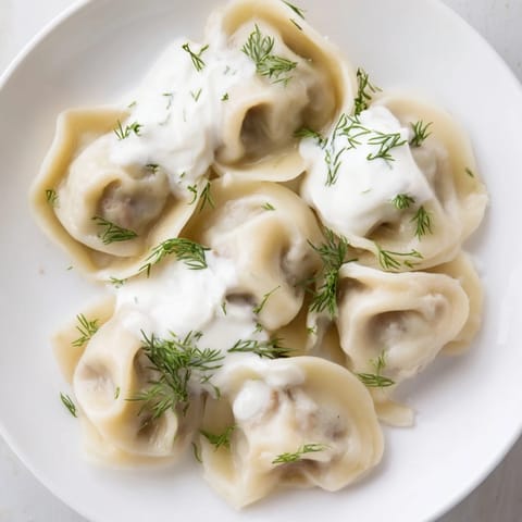 A close-up of delicious Russian pelmeni, filled with savory meat, topped with fresh dill, ready to eat.