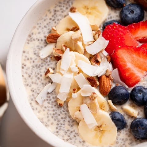 Vibrant chia seed pudding topped with mango chunks, coconut flakes, and a drizzle of maple syrup.  