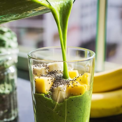 Two tall glasses of refreshing Spinach-Hidden Smoothie garnished with a fresh mint sprig, perfect for a healthy breakfast or snack.