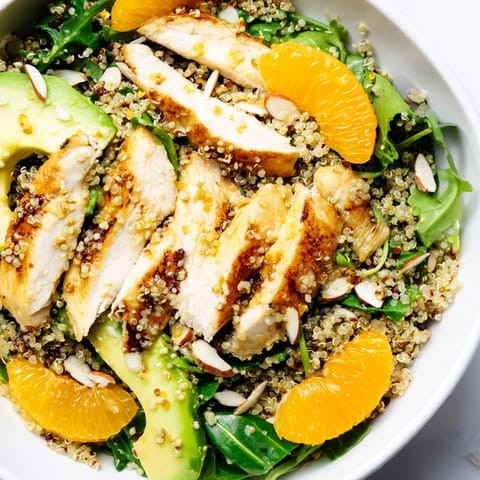 A Citrus Herb Chicken Salad Bowl showcases juicy orange slices, creamy avocado, and toasted almonds on a bed of greens.  