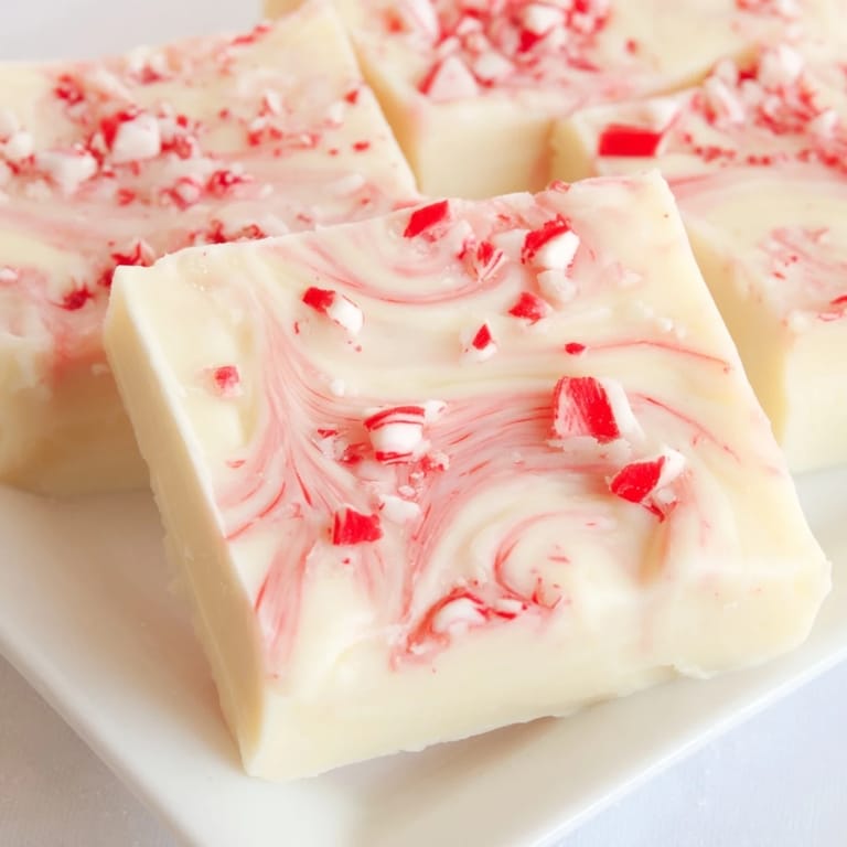 A close-up of holiday White Chocolate Peppermint Bark Fudge showing the creamy white base with crushed peppermint.