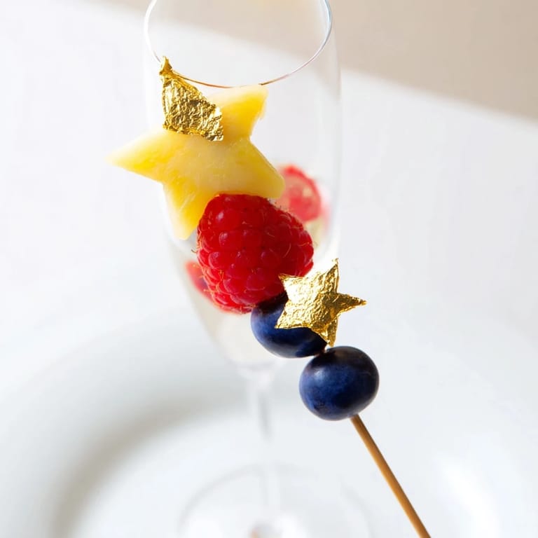 These elegant fruit garnishes for champagne flutes showcase beautifully arranged slices and fresh raspberries ready to be enjoyed.