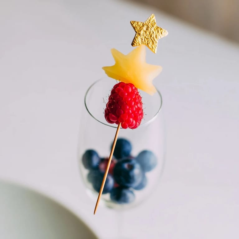 Enjoy a close-up of champagne flute fruit garnishes, ready to enhance the New Year's eve bubbly experience and adding fresh flavors.