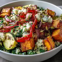 Warm salad bowl filled with quinoa, roasted sweet potatoes, and wilted spinach, drizzled with a bright, homemade warm vinaigrette.