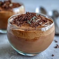 Silky hojicha mousse with a delicate roasted tea aroma, served in elegant glasses and garnished with toasted hojicha leaves.