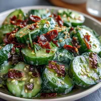 Crispy smashed cucumbers tossed in a tangy garlic chili oil dressing, topped with sesame seeds.